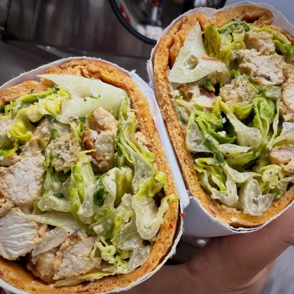 Two pita sandwiches, cut in half, filled with chicken, lettuce, and creamy dressing.